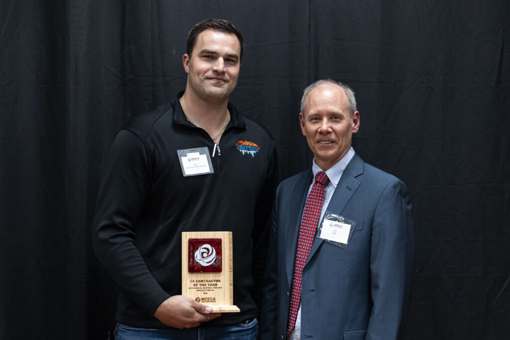A MEECA award recipient posing with his plaque and a presenter at the MEECA award ceremony.