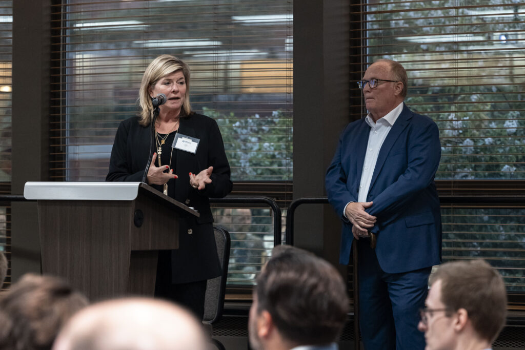 Two MEECA members speaking at the podium at the MEECA award ceremony.